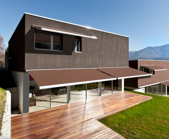 Casa moderna con fachada de madera y grandes ventanales, rodeada de naturaleza.