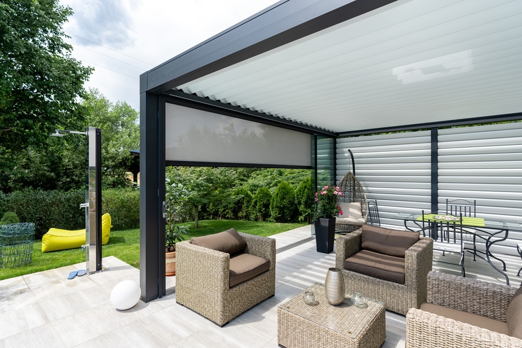 Zona de estar al aire libre con muebles de jardín y vegetación alrededor.